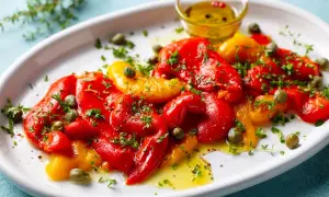 Poivrons marinés rouges et jaunes, arrosés d'huile d'olive et parsemés de câpres et de persil frais. Un délice coloré.