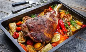 Un plat appétissant d'épaule d'agneau au four, rôti à la perfection avec des légumes colorés comme des poivrons, des tomates et de l'ail.