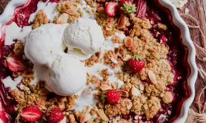 Un délicieux crumble rhubarbe fraise, garni de boules de glace à la vanille fondante et d'amandes effilées.