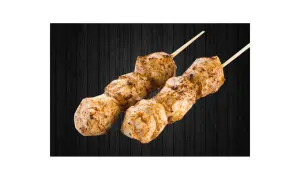 Deux brochettes de boulettes de poulet yakitori grillées, sur fond de bois sombre.