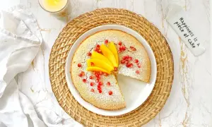 Un délicieux flan coco saupoudré de sucre glace, garni de mangue et de grenades. Une part manque, invitant à la gourmandise.
