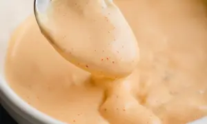Une cuillère de sauce Big Mac crémeuse, parsemée de petites touches de paprika, prête à être dégustée.