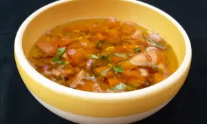 Un bol jaune contient une sauce vierge fraîche, avec des dés de tomates, des herbes vertes et une vinaigrette translucide.