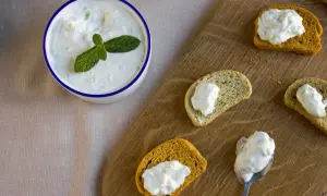 Un bol de tzatziki frais garni de menthe, servi avec des toasts. Une recette facile à partager !