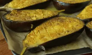 Aubergines au four, coupées en deux et garnies d'une préparation dorée, prêtes à être dégustées.