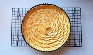 Tarte aux pommes recette de maman, magnifiquement décorée de fines tranches de pommes disposées en spirale sur une pâte dorée.