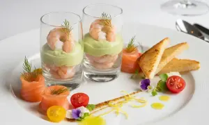 Une délicieuse entrée froide : crevettes et avocat en verrine, saumon roulé, toasts grillés, tomates cerises et fleurs comestibles.