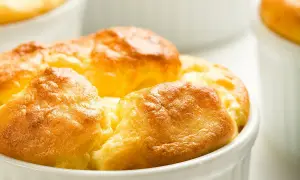 Soufflés au fromage dorés et gonflés dans leurs ramequins, prêts à être dégustés. Une recette simple pour un plat aérien.