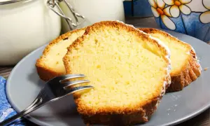 Tranches de gâteau au yaourt moelleux, saupoudrées de sucre glace, sur une assiette grise avec une fourchette.