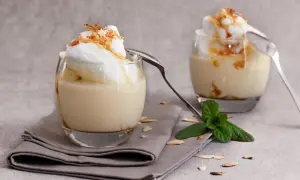 Deux verres de délicieux oeufs à la neige, surmontés de crème et de caramel, avec une touche de menthe fraîche.