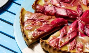 Tarte à la rhubarbe sur pâte feuilletée, garnie de fruits rouges et d'une crème dorée. Un délice estival.