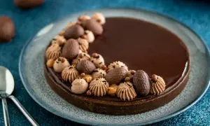 Délicieuse tarte chocolat caramel, ornée d'œufs en chocolat et de touches de crème, prête à être dégustée.