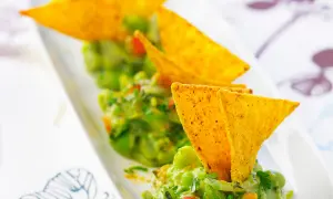 Guacamole maison, une recette facile et savoureuse. Des chips tortilla plongent dans ce délice vert.
