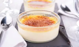 Deux délicieux crèmes brûlées, leur croûte caramélisée craquante, prêts à être dégustés avec une cuillère et une gousse de vanille.