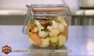 Un bocal de pickles de légumes colorés, comme ceux préparés par un Top Chef, rempli de chou-fleur, carottes et oignons.