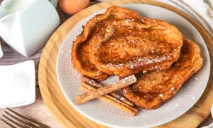 Trois tranches de pain perdu dorées, saupoudrées de sucre glace et garnies de bâtons de cannelle. Un délice pour le petit-déjeuner.