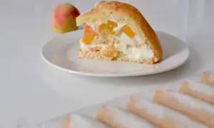 Tranche de charlotte aux fruits et fromage blanc, garnie de morceaux de pêche et de crème onctueuse. Un délice fruité et léger.