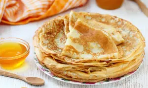Pile de crêpes dorées, accompagnées d'un bol de miel. Parfait pour une recette pâte à crêpe facile sans repos.