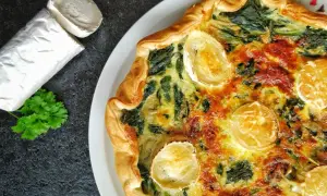 Tarte épinard chèvre dorée, avec du fromage de chèvre frais à côté et une touche de persil.