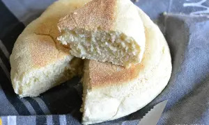 Un pain à la poêle, moelleux et doré, coupé en deux pour révéler sa mie aérée. Parfait pour le petit-déjeuner.