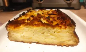 Tranche épaisse d'un délicieux cake aux pommes, avec une croûte dorée et caramélisée.