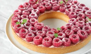 Une magnifique tarte à la framboise facile, garnie de fruits rouges frais et saupoudrée de sucre glace. Parfaite pour un dessert gourmand.