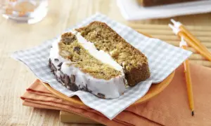 Tranche de carrot cake moelleux avec glaçage blanc et copeaux de chocolat. Un délice à savourer !