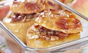 Deux pommes au four dorées, garnies de noix et de raisins secs, nappées d'un sirop brillant. Un délice gourmand.