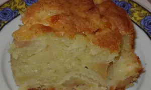 Une part de moelleux aux pommes, avec sa croûte dorée et sa mie tendre, prête à être dégustée.