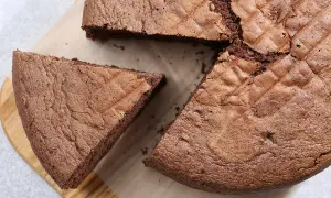 Un gâteau chocolat Pierre Hermé, moelleux et aérien, avec une part coupée sur une planche en bois.
