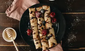 Crêpes roulées garnies de fruits rouges et de chocolat, prêtes à être dégustées. Une recette simple et gourmande pour le petit-déjeuner ou le goûter.