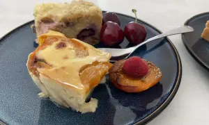 Un délice de clafoutis abricot, servi avec des cerises et une framboise sur une pêche rôtie.