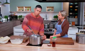Un homme et une femme préparent un plat dans une cuisine. Le bouillon de poulet mijote dans une grande casserole.