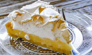 Une part de tarte au citron meringuée, avec sa crème jaune acidulée et sa meringue dorée, prête à être dégustée.