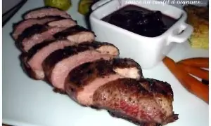 Magret de canard tranché, servi avec une sauce au confit d'oignons. Un délice pour les gourmands.