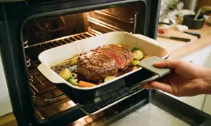 Un rosbeef juteux avec des légumes rôtis sort du four. Le temps de cuisson au four est presque terminé, prêt à être dégusté.