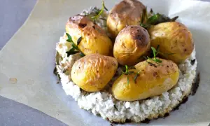 Pommes de terre nouvelles dorées, garnies d'herbes fraîches, sur un lit de purée de chou-fleur. La cuisson pomme de terre nouvelle est réussie.