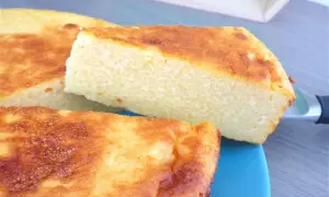 Un gâteau arabe semoule extra fine, doré et moelleux, servi sur une assiette bleue. Sa texture légère promet un délice.