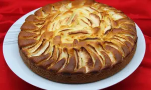 Un délicieux gâteau yaourt pomme, doré et appétissant, orné de fines lamelles de pommes disposées en rosace sur le dessus.