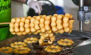 Des beignets dorés, en forme de chaînette, sont frits dans l'huile. La pâte à beignets prend forme, prête à être dégustée.