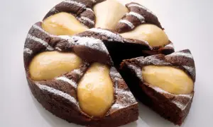 Gâteau poire chocolat, un délice moelleux parsemé de sucre glace, avec des poires fondantes incrustées dans la pâte.