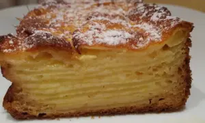 Tranche d'un gâteau aux pommes, feuilleté et doré, saupoudré de sucre glace. Un délice invisible aux pommes.