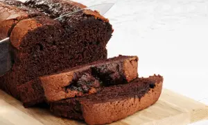 Un délicieux gâteau au chocolat sans beurre, coupé en tranches sur une planche en bois. Sa texture moelleuse et son goût intense invitent à la gourmandise.
