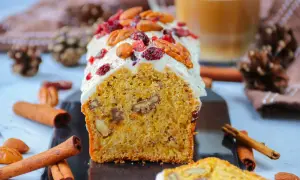 Un délicieux carotte cake glacé, garni de noix et de canneberges, prêt à être dégusté. Une recette parfaite pour le goûter.