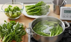 Préparation pour la cuisson d'épinards frais. Des légumes verts bouillent dans une casserole, d'autres sont prêts à être cuisinés.