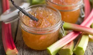 Confiture de rhubarbe maison dans un bocal, avec des tiges de rhubarbe fraîches et une gousse de vanille.