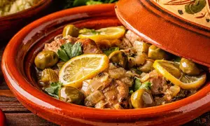 Un plat de tajine aux citrons confits, olives vertes et herbes fraîches, prêt à être dégusté.