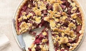 Tarte crumble à la rhubarbe, une délicieuse recette avec rhubarbe, garnie de morceaux de fruits rouges et d'une pâte croustillante.
