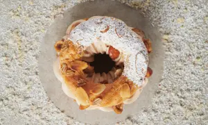 Un délicieux Paris-Brest, saupoudré de sucre glace et garni d'amandes grillées, attend d'être dégusté.