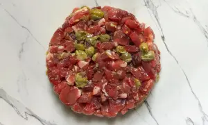 Un délicieux tartare de bœuf gastronomique, préparé avec soin et garni de câpres, prêt à être dégusté.